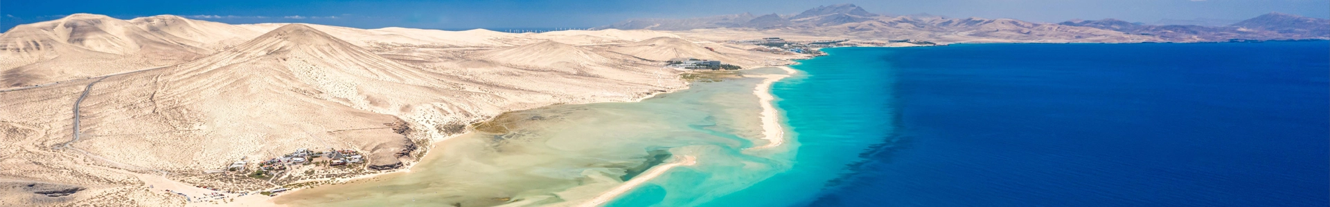 Plages et eaux turquoise de Fuerteventura Vue aérienne spectaculaire des plages de sable blanc et des eaux turquoise de Fuerteventura, avec des montagnes désertiques en arrière-plan