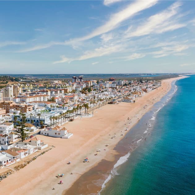 Vue aérienne des plages de Huelva avec des bâtiments côtiers et une mer d’un bleu profond