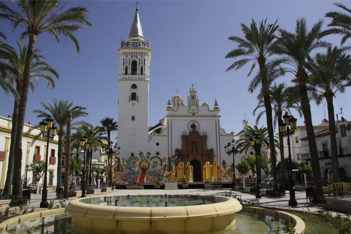 Place centrale de Huelva avec son église emblématique entourée de palmiers et d'une fontaine