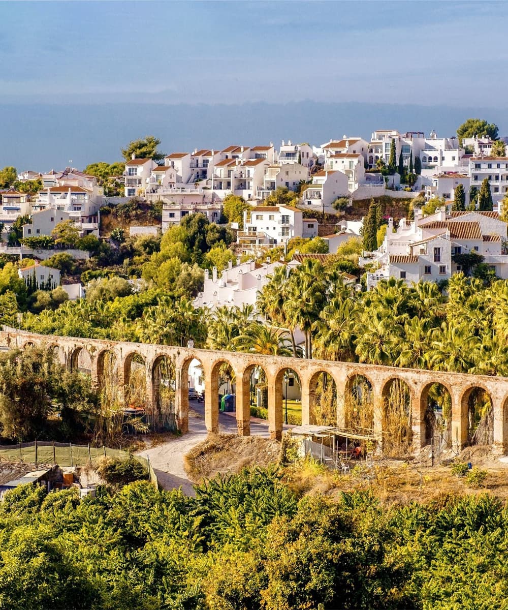 Vue panoramique de Nerja Vue panoramique de Nerja avec ses maisons blanches nichées sur les collines et un aqueduc historique entouré de verdure
