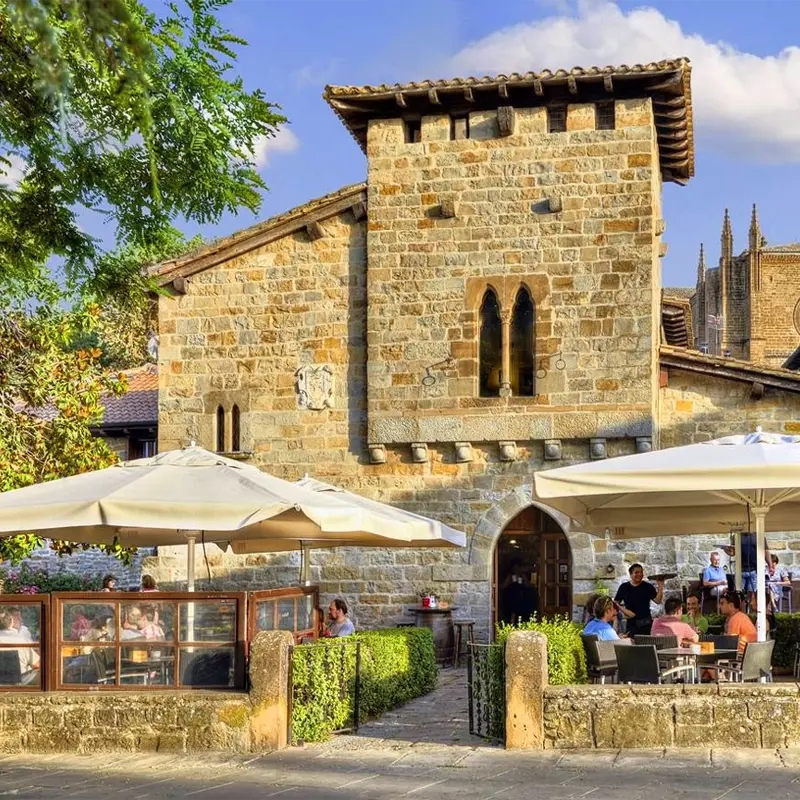 Terrasse de restaurant avec parasols devant un bâtiment en pierre historique