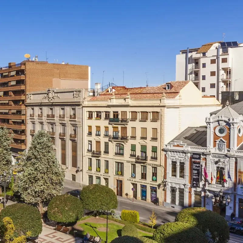 Vue sur des bâtiments anciens et modernes autour d’un petit parc urbain