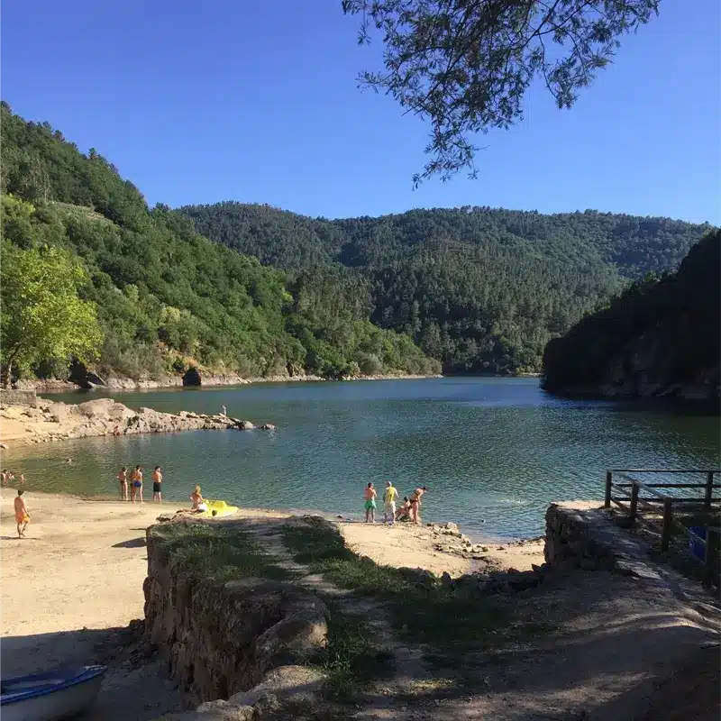 Plage fluviale en Galice avec forêt verdoyante et baignade en famille