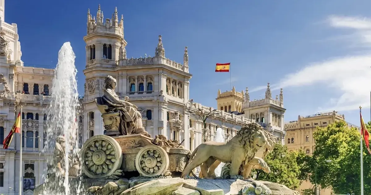 Plaza de Cibeles à Madrid avec la fontaine emblématique de la déesse Cybèle entourée de lions, bâtiments historiques et ciel bleu en arrière-plan