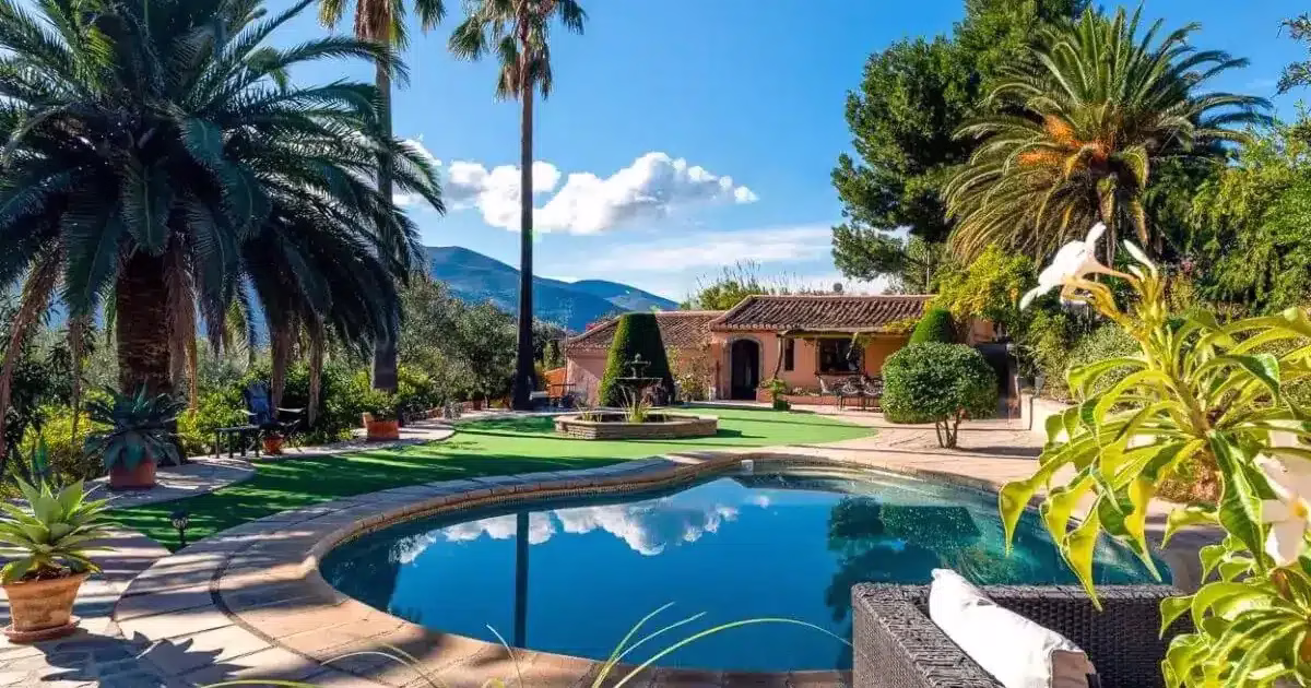 Villa espagnole avec piscine ronde, jardin méditerranéen et palmiers sous un ciel bleu