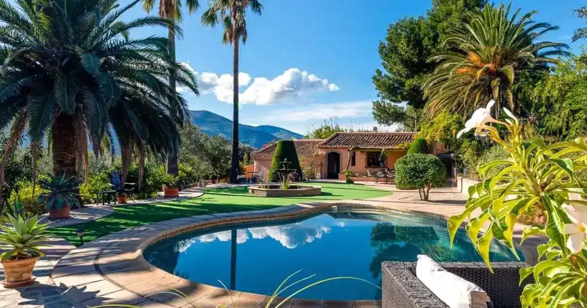 Villa espagnole avec piscine ronde, jardin méditerranéen et palmiers sous un ciel bleu
