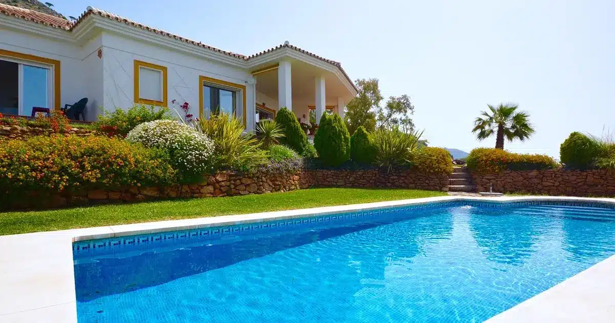 Belle maison espagnole avec piscine extérieure, entourée d’un jardin fleuri et d’une terrasse ensoleillée.