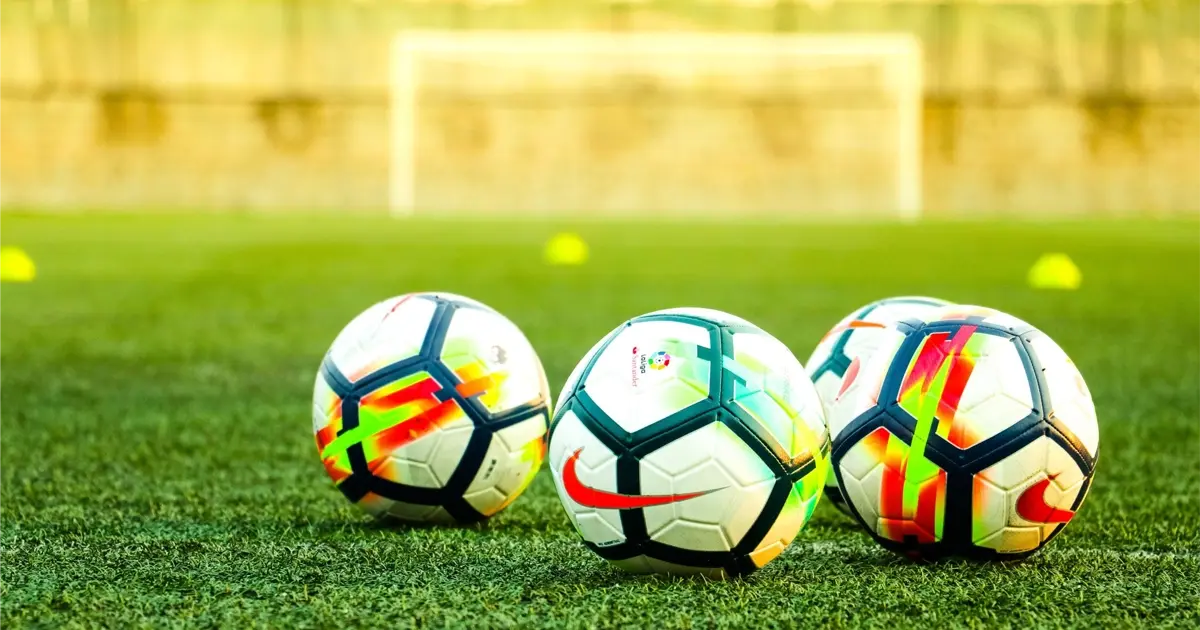 Ballons de football sur un terrain en Espagne, illustrant la culture sportive et l’importance du foot