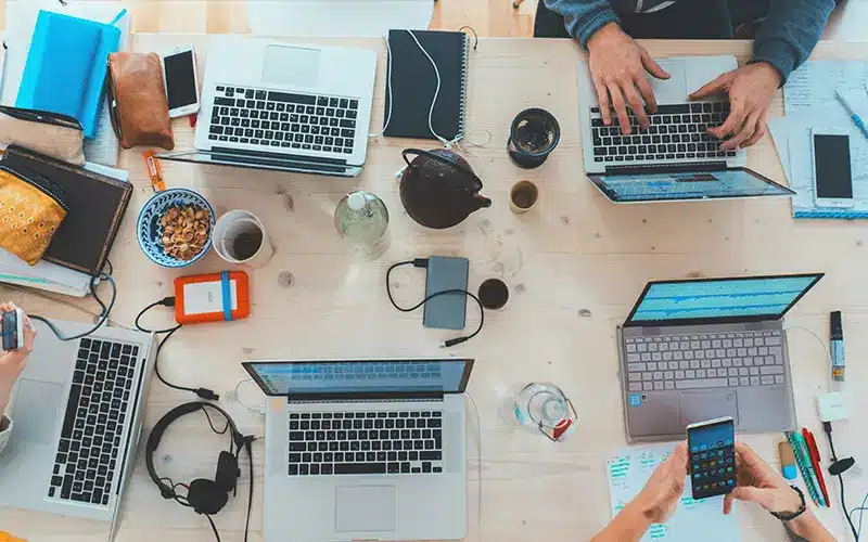 Espace de coworking avec ordinateurs portables et smartphones, illustrant l’écosystème des startups en Espagne